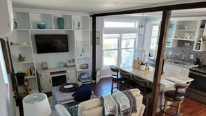 A living room with a sofa, TV, and a dining area with chairs and a table.