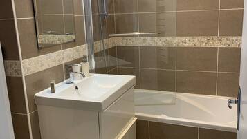 Een bad/douchecombinatie, een haardroger, handdoeken, toiletpapier