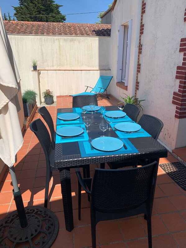 A patio with a table set for four, surrounded by black wicker chairs, and a small potted plant on the wall. - Apartment for 5 people, 200 m from the sea, Pornic Gourmalon (Pornic)
