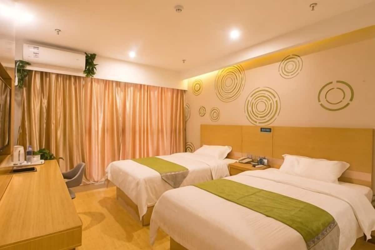 Habitación de hotel con dos camas, un escritorio, una silla, un equipo de aire acondicionado y una cortina.