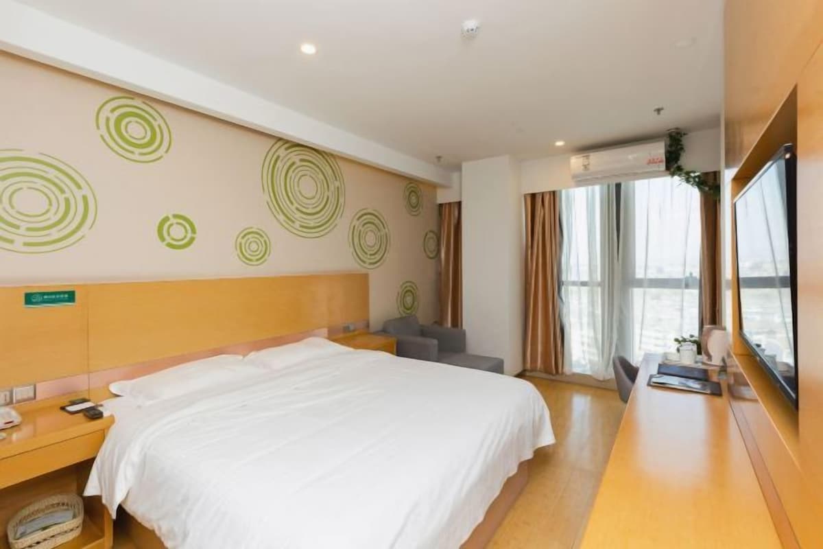 Una camera d'albergo con un letto grande, una scrivania, una sedia e una finestra con tende.