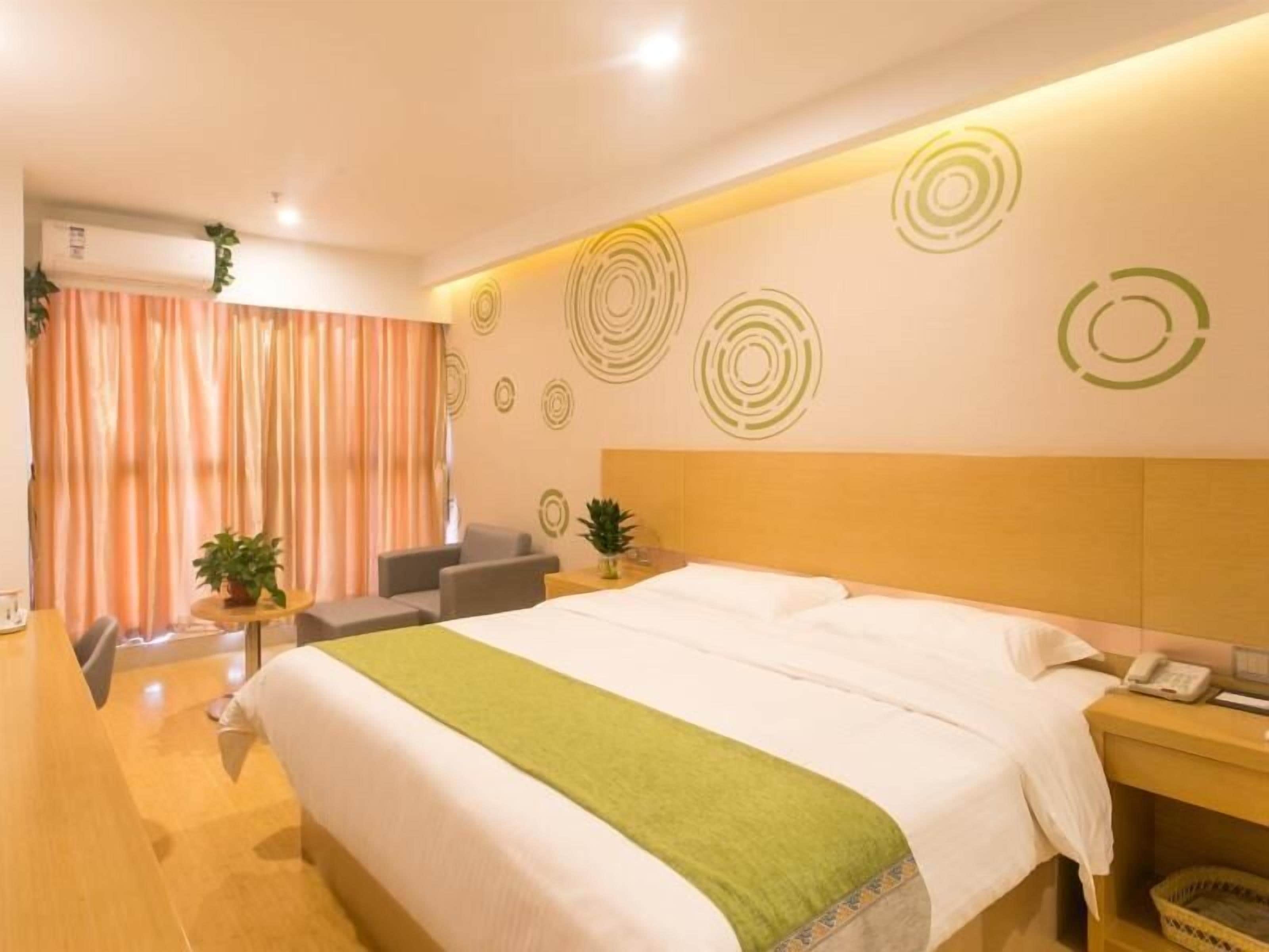 Habitación de hotel con cama, escritorio, silla y una mesita con una planta.