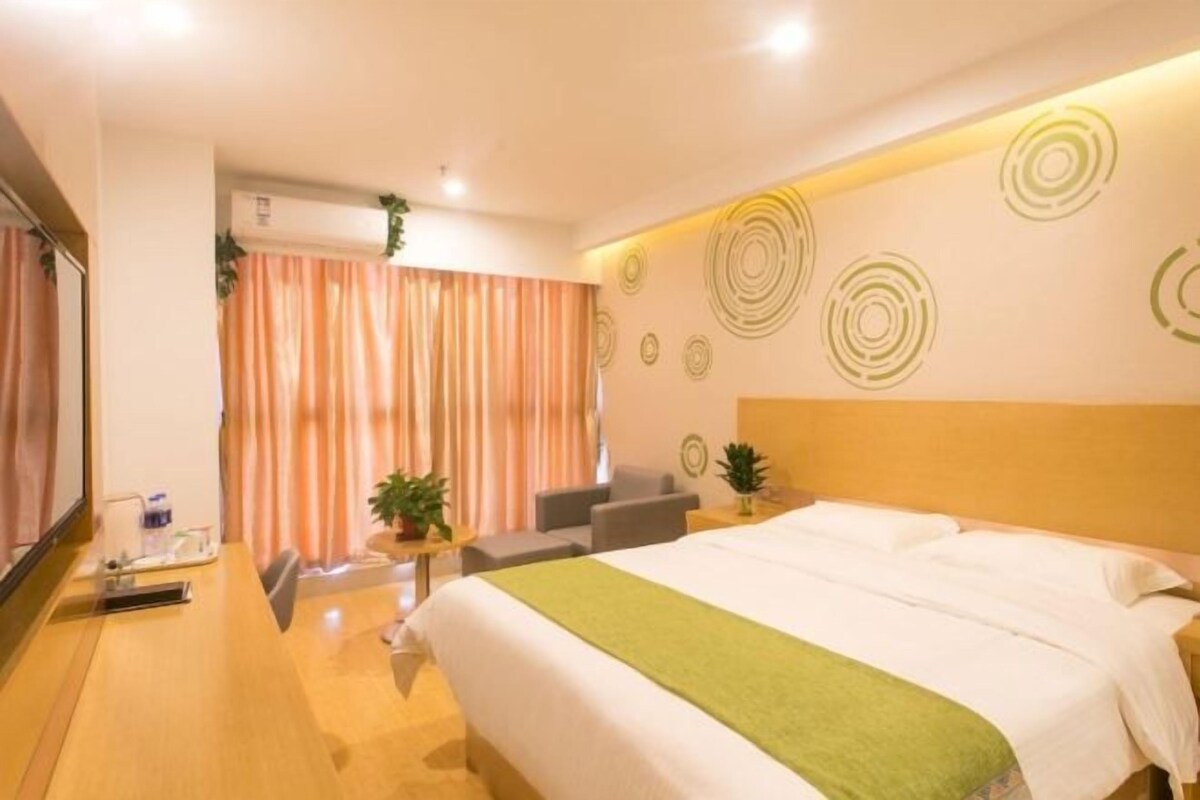Habitación de hotel con cama, escritorio, silla, mesita con una planta y pared con diseños circulares.