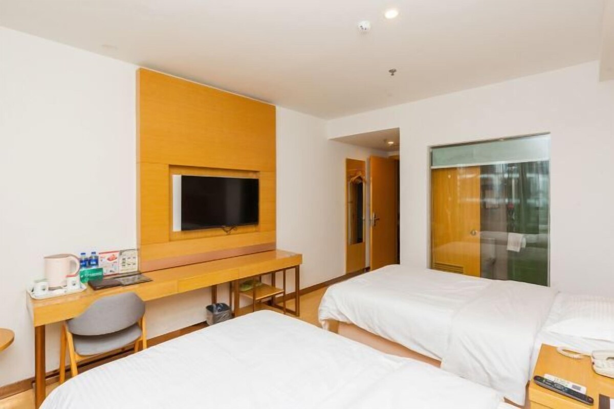 Habitación de hotel con dos camas, un escritorio con televisor y un armario.
