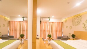 Une chambre d’hôtel avec deux lits, une table en bois et un miroir.