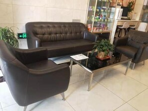 A lobby with a brown leather sofa, a glass coffee table, and a small plant. - Greentree Inn Suzhou Tai Lake Xukou Town Government Express Hotel (Suzhou)