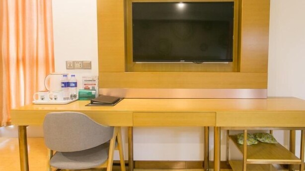 Een kamer met een houten bureau, een stoel, een raam en een bed met kussens.