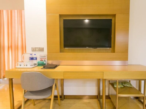 Una habitación con un escritorio de madera, una silla, una ventana y una cama con almohadas.