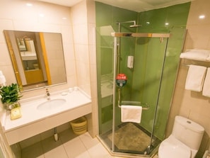 Un baño moderno con ducha de vidrio, lavamanos con espejo y retrete.