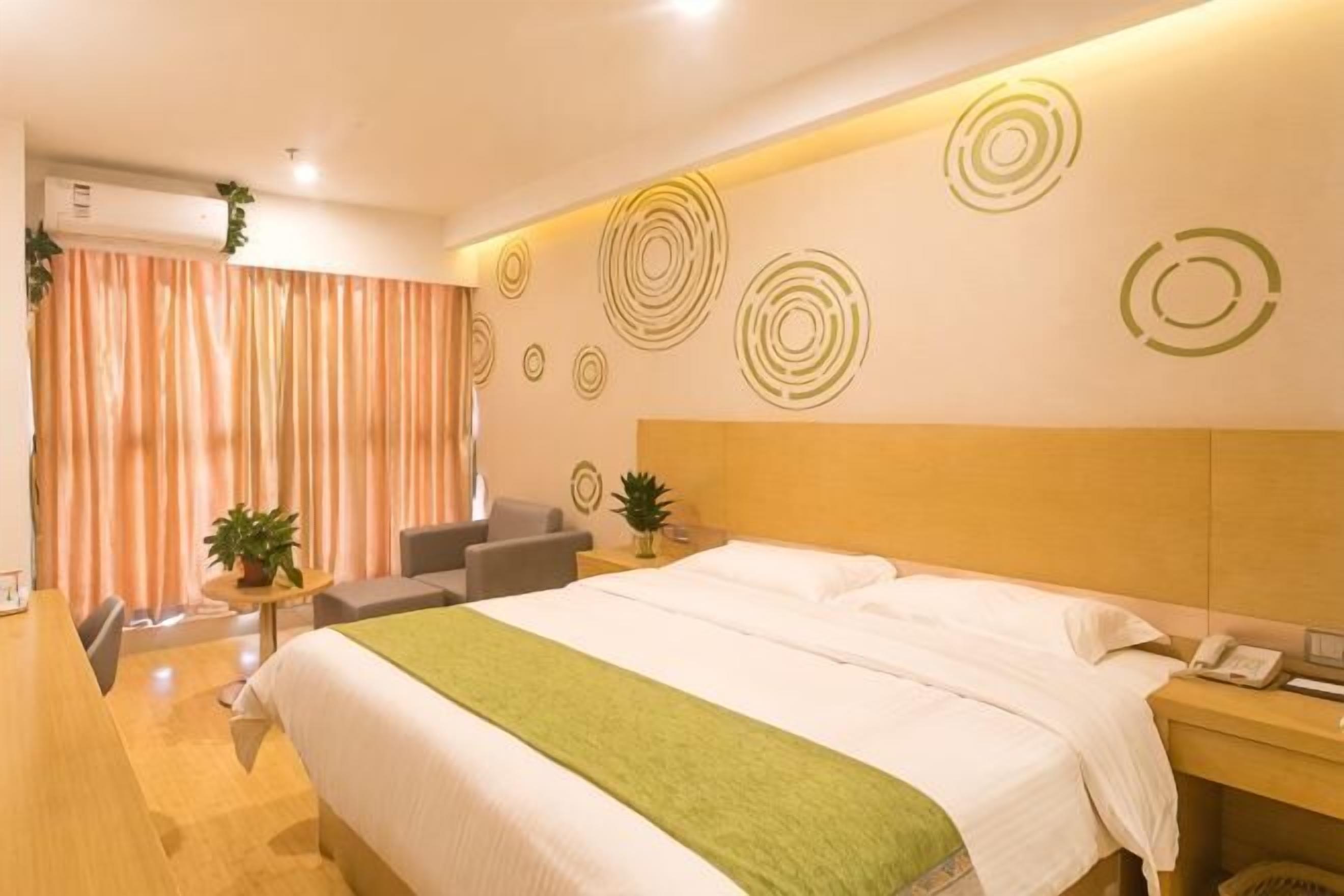 Una habitación de hotel con cama, mesita de noche, silla y una pequeña mesa con una planta.