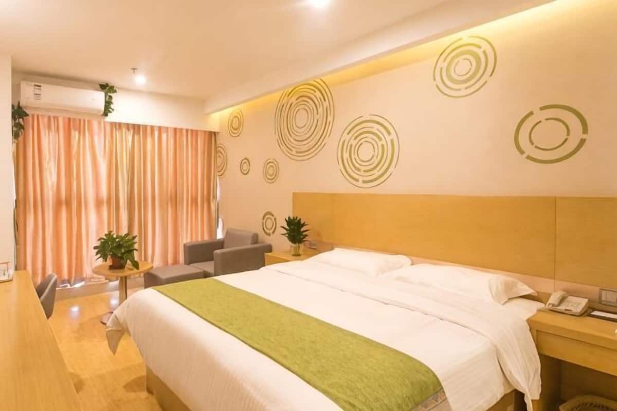 Una habitación de hotel con cama, mesita de noche, silla y una pequeña mesa con una planta.