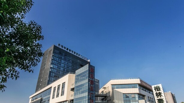 Un hôtel moderne doté d’une façade en verre remarquable, d’une entrée bien visible et surplombant un ciel dégagé.