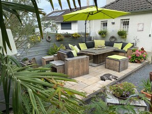 A patio with wooden furniture, a bright yellow umbrella, and potted plants.