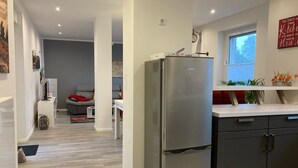 Eine moderne Küche mit einem Edelstahlkühlschrank, dunklen Schränken und einem Fenster, das für natürliches Licht sorgt.