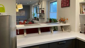 Eine moderne Küche mit weißer Arbeitsplatte, integriertem Backofen und einer roten Akzentwand.