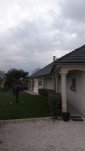 Ein Wohnhaus mit gepflegtem Rasen, einer Palme und einem Schotterweg.