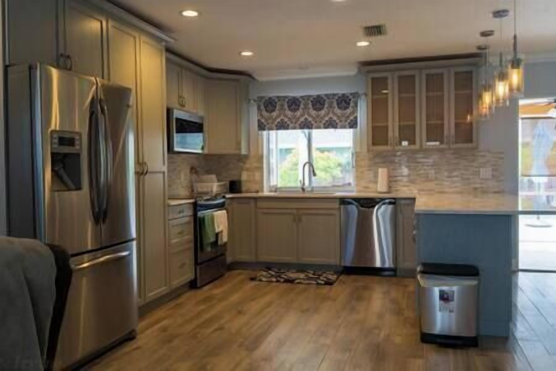 A modern kitchen with stainless steel appliances, a dishwasher, and a window with a view.
