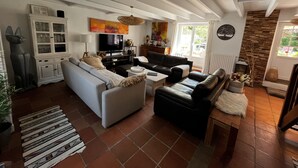 Una sala de estar con un sofá, una mesa de centro y un televisor. Hay un aparador con puertas de vidrio y un cuadro en la pared.