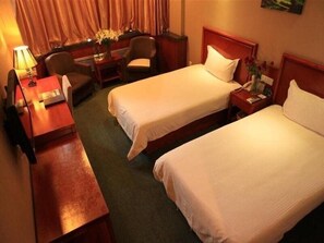 A hotel room with two single beds, a desk with a chair, a lamp, and a small table with a vase of flowers. - Greentree Inn Lanzhou Yantan Road Express Hotel (Lanzhou)