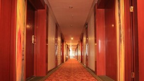 A hotel hallway with red walls and carpet, featuring doors on both sides. - Greentree Inn Lanzhou Yantan Road Express Hotel (Lanzhou)