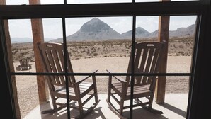 Dos mecedoras mirando un paisaje desértico con montañas al fondo.
