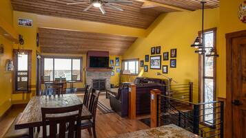 A dining area with a wooden table and chairs, a fireplace, and a staircase with a railing.