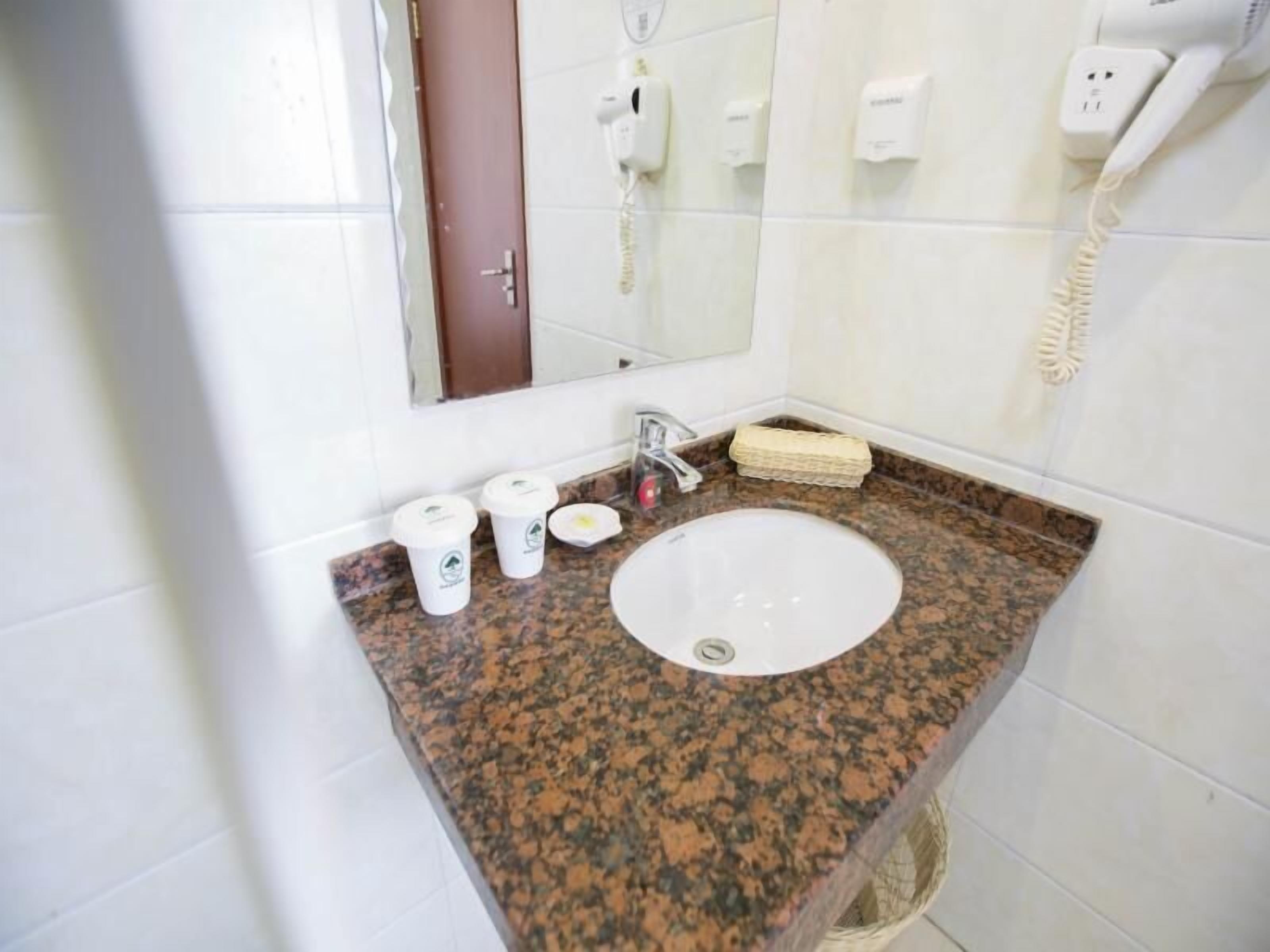 A bathroom with a granite countertop, a sink, a mirror, a hairdryer, and a telephone.