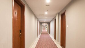 A hotel corridor with wooden doors, a patterned carpet, and recessed lighting. - Greentree Inn Changzhou Wujin Bus Station (Changzhou)