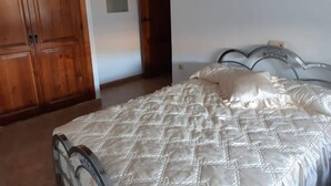 A bedroom with a bed, wooden wardrobe, and a door. - Casa Alba E Irene (Bubión)