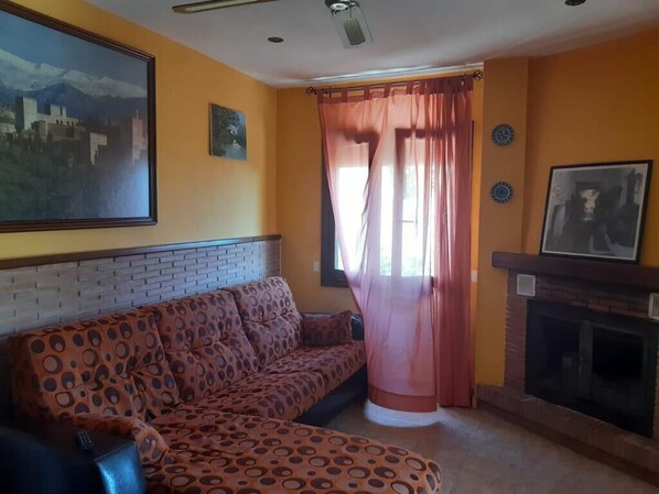 A living room with a patterned sofa, a fireplace, and a large painting on the wall.
