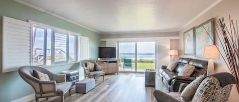 A spacious living room with a large TV, comfortable seating, and a view of the outdoors.