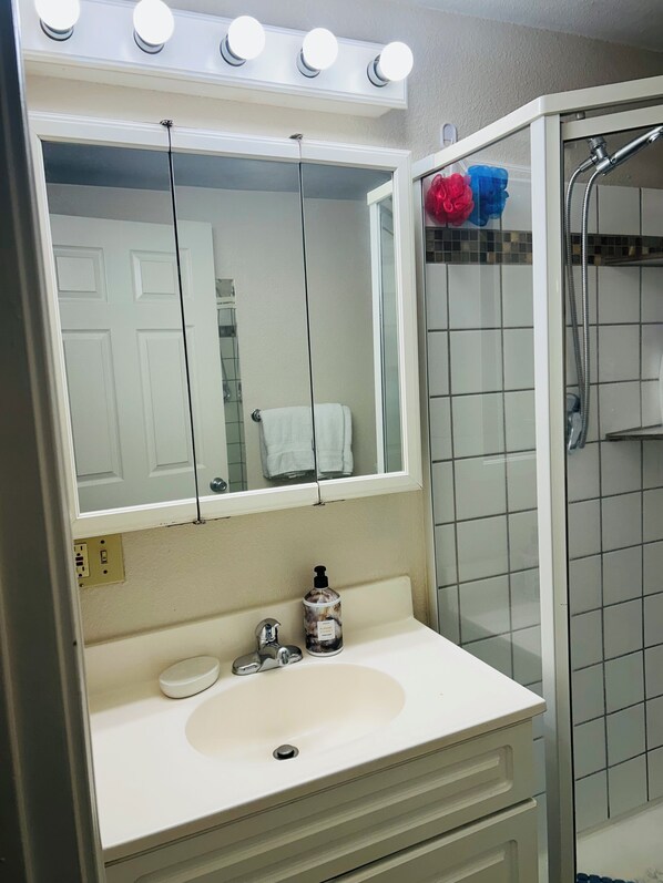 A bathroom with a white sink, a mirror, and a shower.