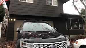 A black Ford SUV parked in front of a two-story house with a dark brown exterior and white trim. - Emerald City Cozy Studio Suite - Stay near university fun – 5 min drive (Eugene)