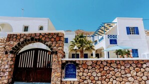 A traditional white building with a stone archway entrance, a staircase, and a sign indicating a hotel named "Villa Spiridonida." - Spiridoula villa (Santorini)