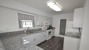 A kitchen with white cabinets, granite countertops, a built-in oven, and a microwave.