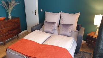 A bedroom with a bed, pillows, a dresser, a nightstand, and a lamp.