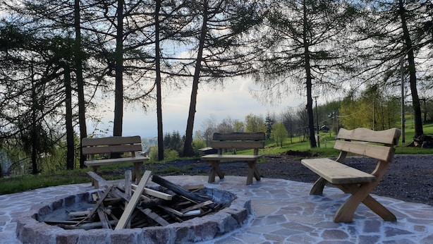 A stone fire pit with benches and a view of a forested area. - Vacation home for 12 people, 8 rooms, 4 bathrooms with fireplace and large lounge (Altenberg)