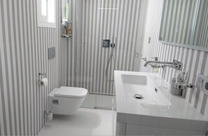 Features a sleek design with a striped wallpaper pattern, toilet, shower, and sink with a mirror.
