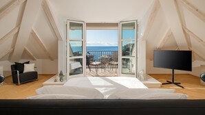 Une chambre dotée d’un grand lit, d’une télévision et d’un balcon offrant une vue sur la mer.