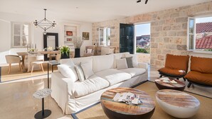 Un salon spacieux avec un canapé blanc, deux tables basses et un coin repas comprenant une table et des chaises.