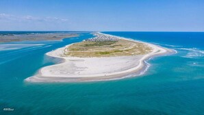 Vista aérea de una zona costera con playa de arena y aguas azules cristalinas.