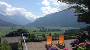 A terrace with two orange chairs overlooking a valley with mountains in the background. - Exclusive Chalet with amazing view (Benken)