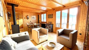 A cozy wooden cabin interior with a dining area, two sofas, and a fireplace. - Exclusive Chalet with amazing view (Benken)