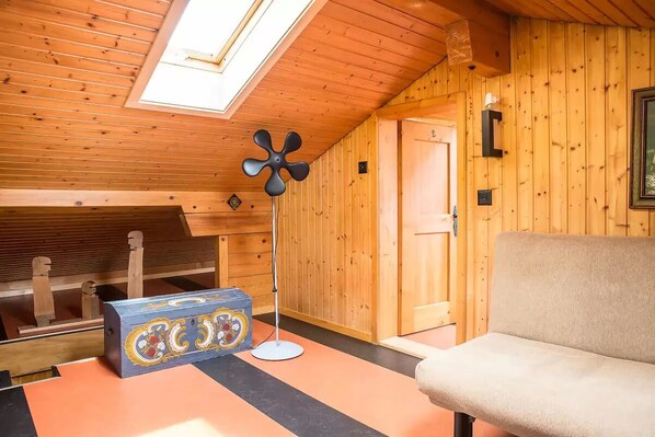 A cozy room with wooden walls, a ceiling fan, a bench, and a decorative box. - Exclusive Chalet with amazing view (Benken)
