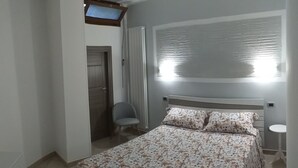 Una camera da letto con un letto, una sedia, un comodino e una finestra con persiane.