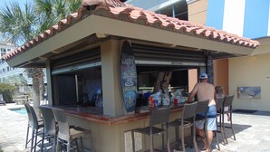 Un espace bar extérieur doté d’un toit en tuiles, de tabourets de bar et d’un panneau d’affichage en ardoise.