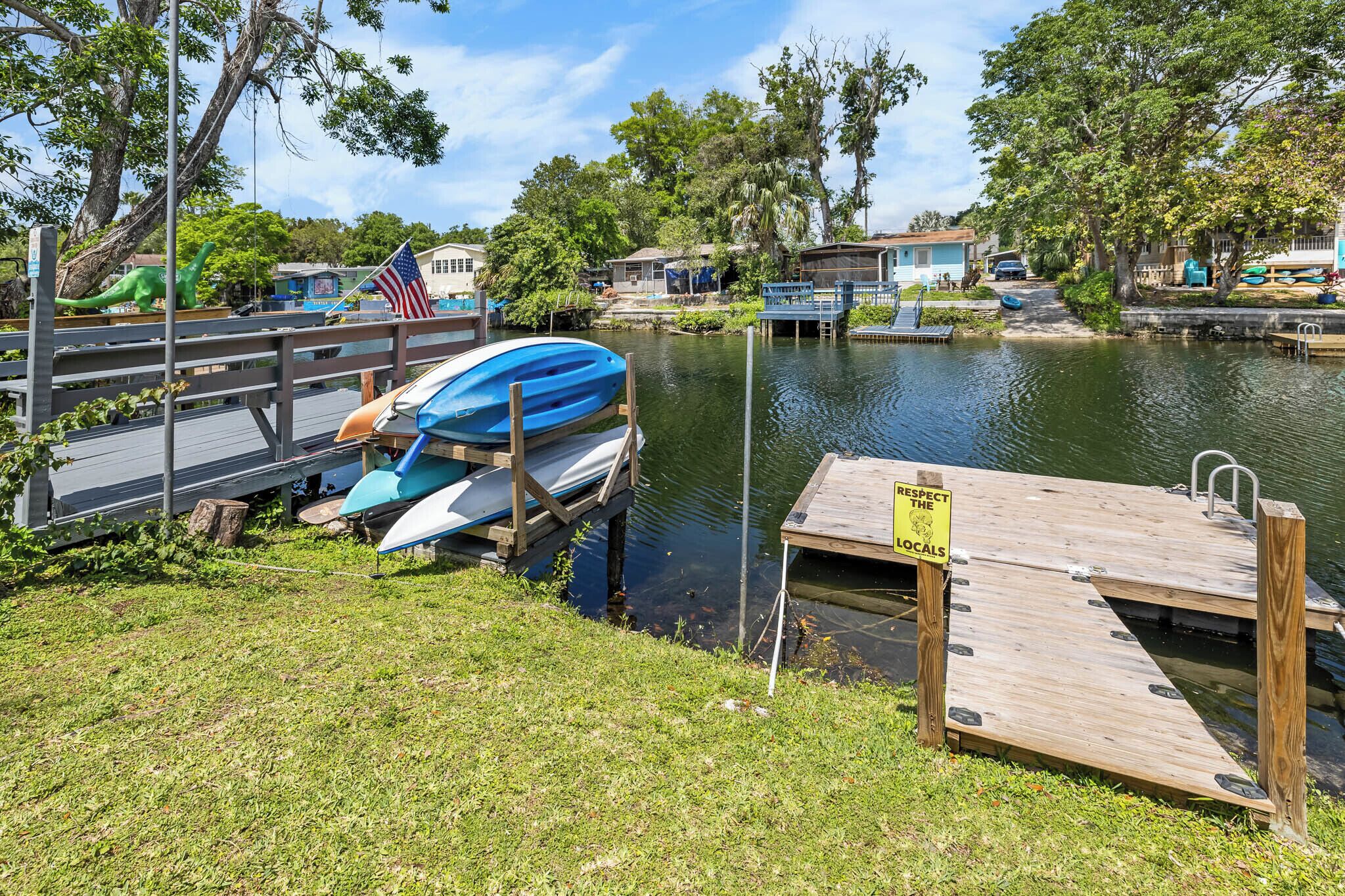 A dock with a blue kayak, a wooden pier, and a sign that reads "RESPECT THE LOCALS".