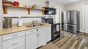 A kitchen with white cabinets, a stainless steel refrigerator, a microwave, and a stove. - Waterfront w access to the Weeki Wachee River & Gulf of Mexico - Dog Friendly! (Spring Hill)