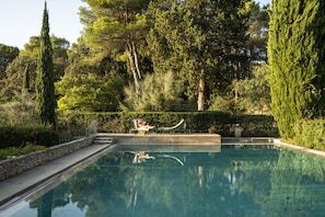 Una piscina con pared de piedra y una tumbona.