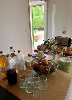 A kitchen counter with various food items, including bread, cheese, and fruits, and several bottles and glasses.